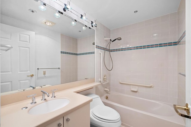 full bathroom featuring vanity, tiled shower / bath, and toilet