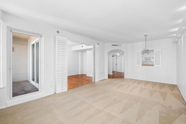 spare room featuring an inviting chandelier and light colored carpet