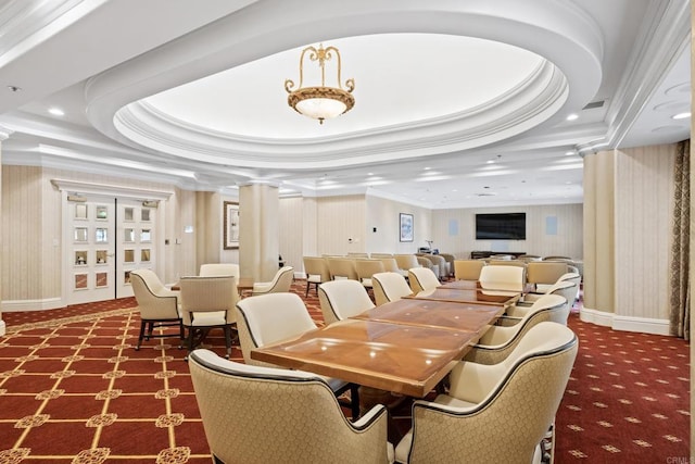 carpeted dining space with ornamental molding, a raised ceiling, and decorative columns