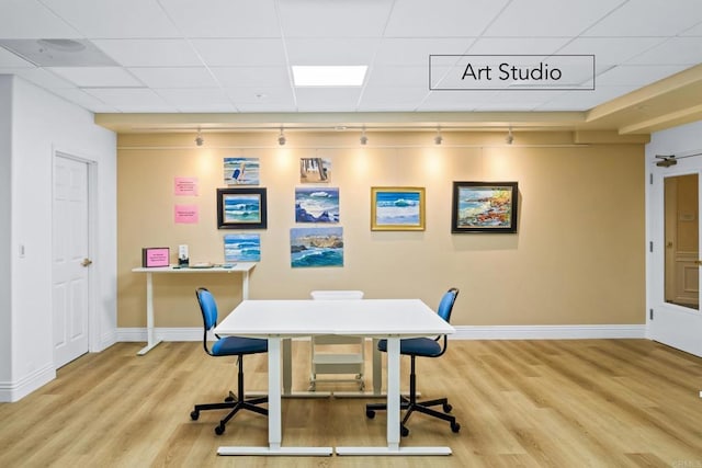 office area with light hardwood / wood-style flooring, track lighting, and a paneled ceiling