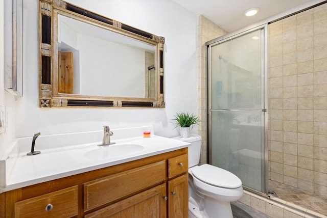 bathroom with a shower with door, vanity, and toilet