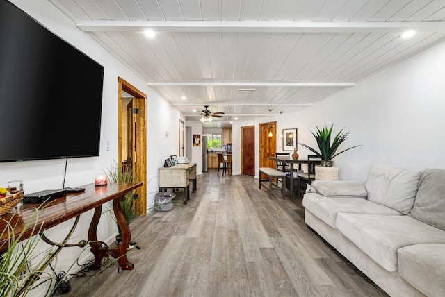 living room with ceiling fan, beamed ceiling, wood-type flooring, and wooden ceiling