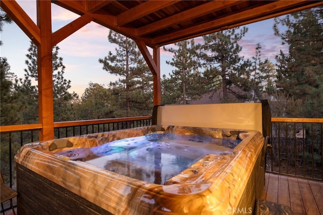 deck at dusk featuring a hot tub