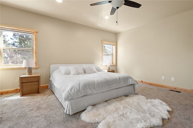 bedroom featuring multiple windows, ceiling fan, and light colored carpet