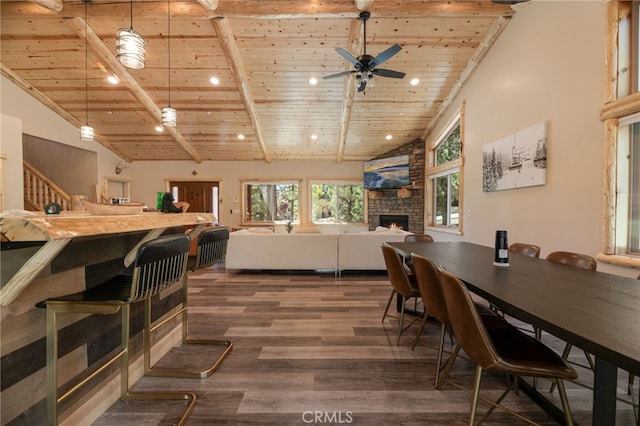 dining area featuring wood ceiling, a stone fireplace, dark wood-style floors, high vaulted ceiling, and a ceiling fan