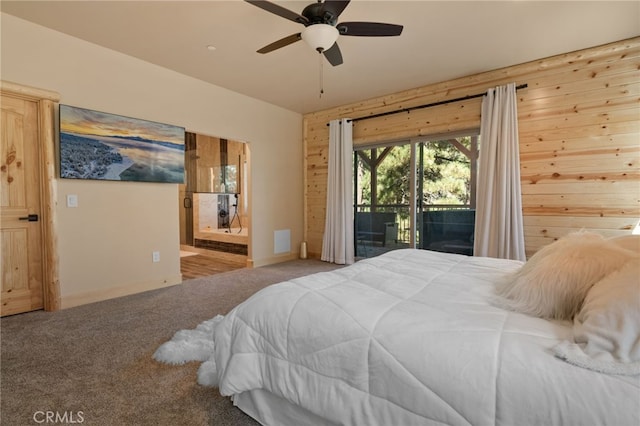 bedroom with ensuite bathroom, wooden walls, access to exterior, and carpet flooring