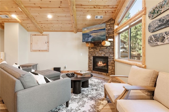 living area with lofted ceiling with beams, visible vents, wood ceiling, and a stone fireplace