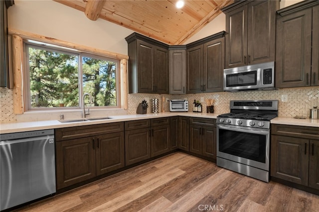 kitchen featuring sink, appliances with stainless steel finishes, lofted ceiling with beams, wooden ceiling, and decorative backsplash