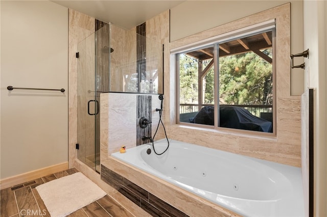 bathroom featuring wood tiled floor, baseboards, a whirlpool tub, and a shower stall