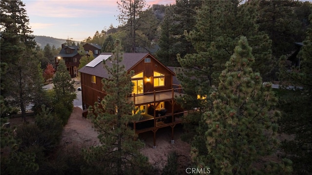 back of property at dusk with a wooded view