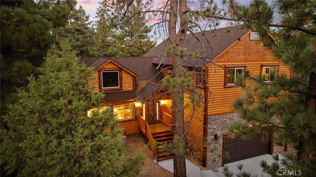 back house at dusk featuring a deck and a garage