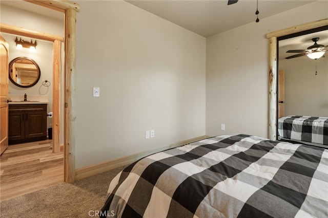 bedroom featuring light colored carpet, a ceiling fan, light wood-style floors, and baseboards