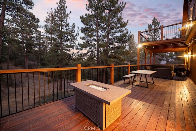 deck at dusk featuring a jacuzzi and a fire pit