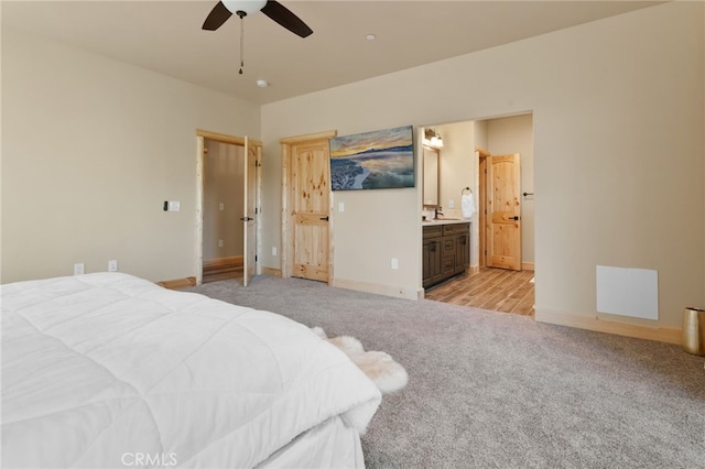 bedroom featuring a sink, ensuite bath, baseboards, and light carpet