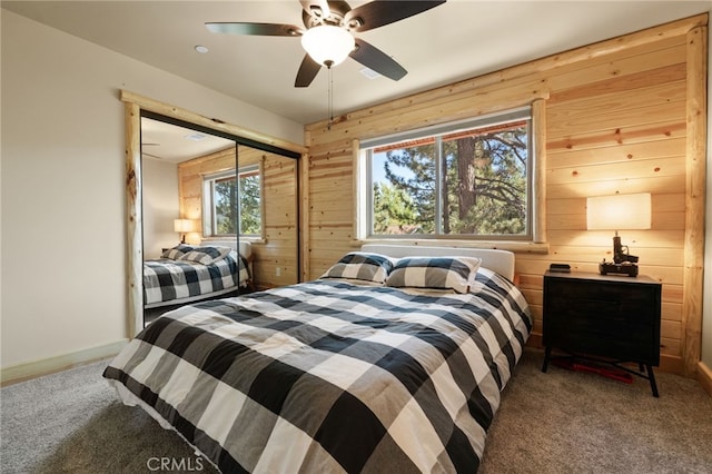 bedroom featuring ceiling fan, wooden walls, a closet, and carpet