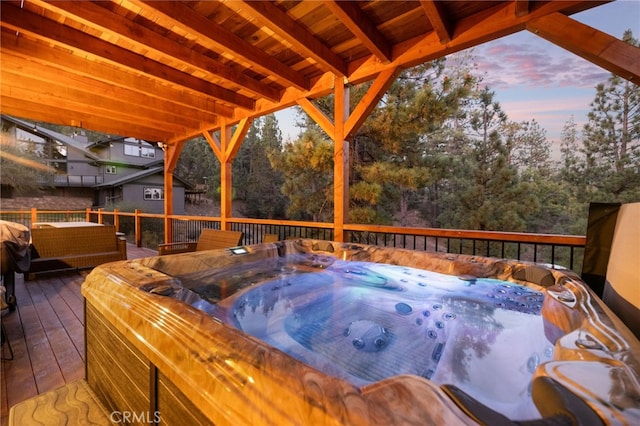 deck at dusk featuring a hot tub