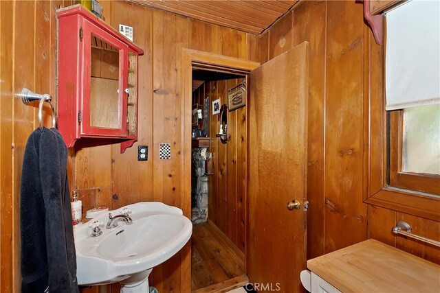 bathroom with wood ceiling, sink, and wooden walls