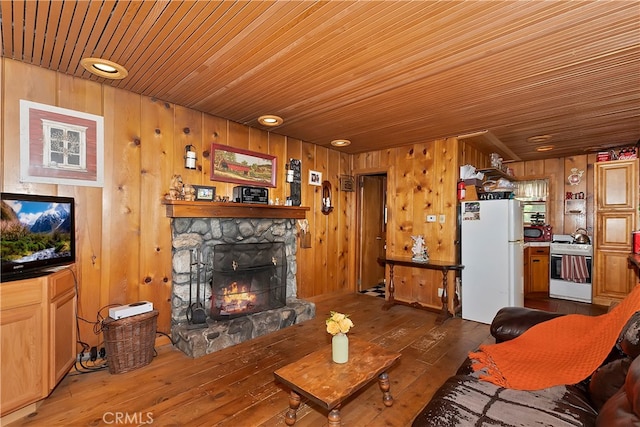 living room featuring dark wood-type flooring, wooden walls, and a stone fireplace