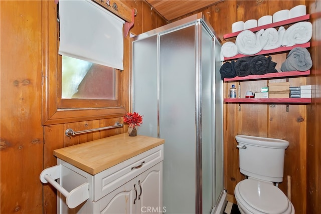 bathroom featuring vanity, wooden walls, toilet, and an enclosed shower