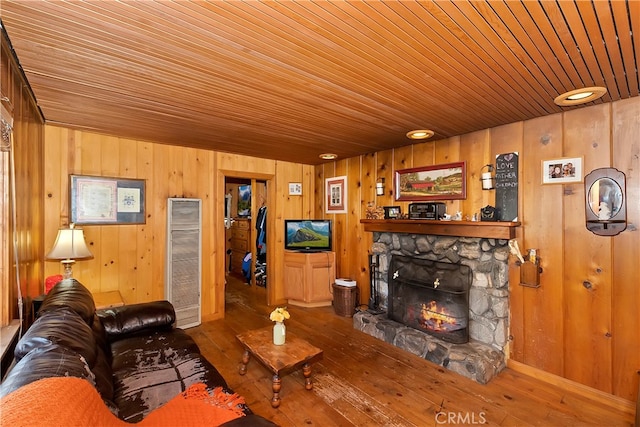 living room with a fireplace, wooden ceiling, hardwood / wood-style flooring, and wooden walls