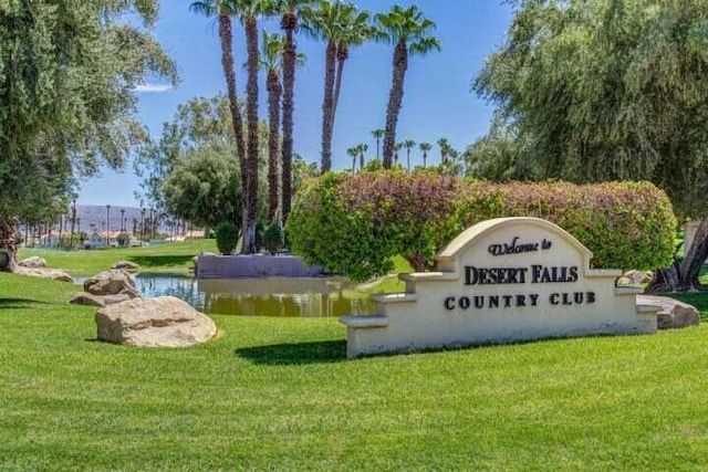 community sign with a water view and a lawn