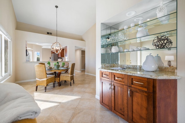 interior space featuring light stone countertops, stainless steel fridge, a chandelier, hanging light fixtures, and light tile patterned flooring