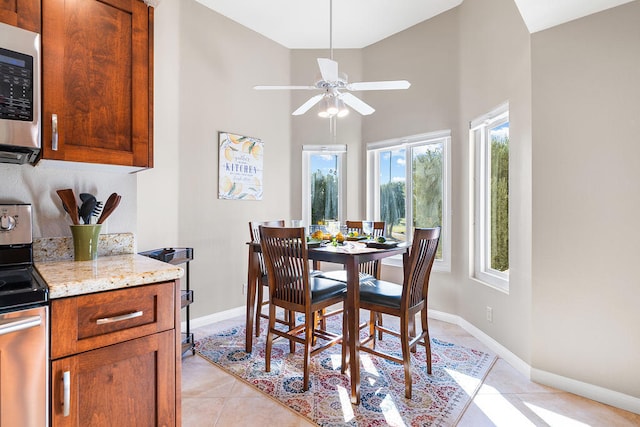 dining area with ceiling fan, high vaulted ceiling, and light tile patterned floors