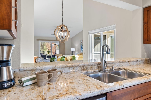 kitchen with lofted ceiling, an inviting chandelier, sink, decorative light fixtures, and light stone counters