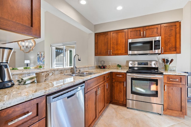 kitchen featuring kitchen peninsula, appliances with stainless steel finishes, light stone counters, sink, and a chandelier