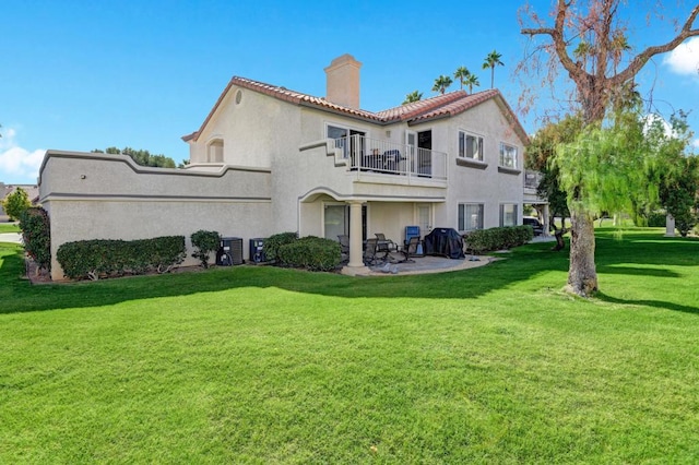 rear view of property with a patio, a balcony, cooling unit, and a lawn