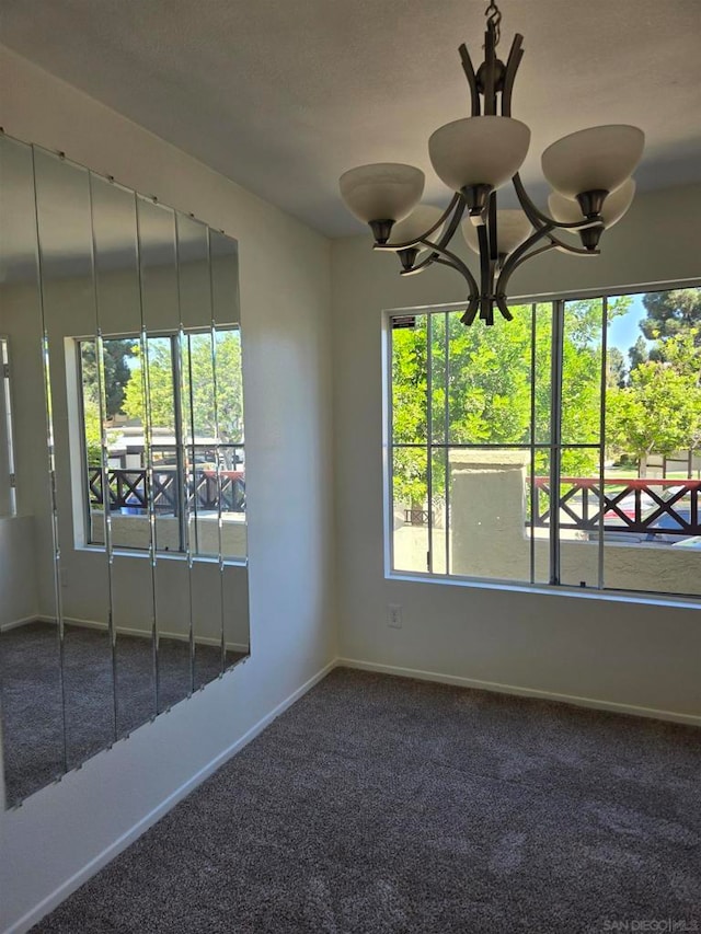 carpeted empty room with a notable chandelier