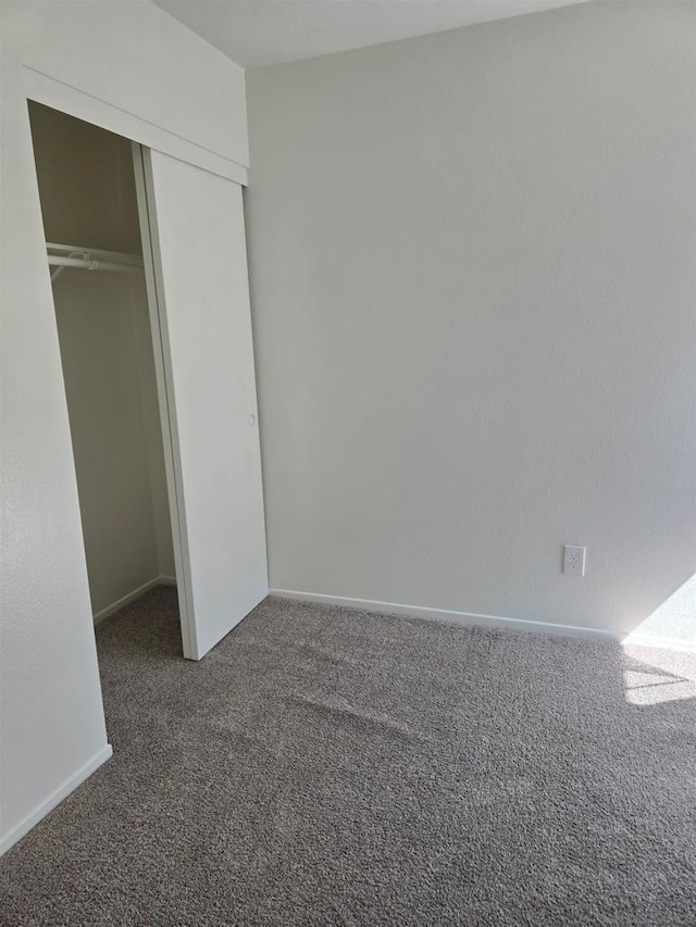 unfurnished bedroom with a closet and dark carpet