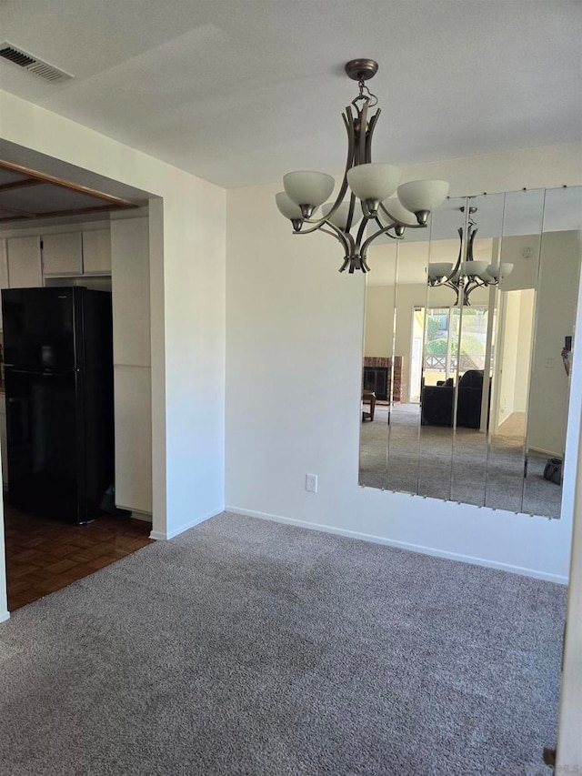 spare room with a notable chandelier and dark colored carpet