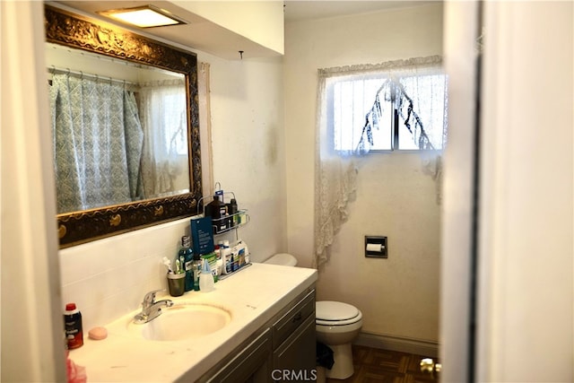 bathroom with vanity, toilet, and tasteful backsplash