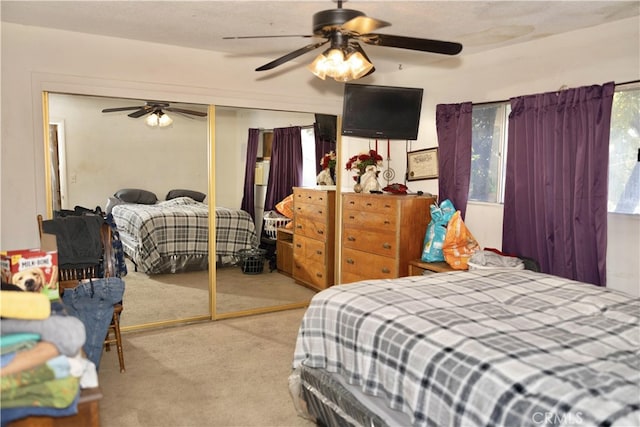 carpeted bedroom with ceiling fan and a closet