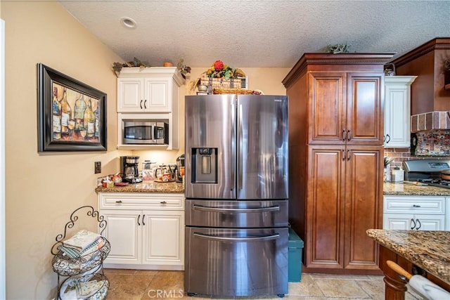 kitchen featuring appliances with stainless steel finishes, a textured ceiling, light stone counters, and backsplash