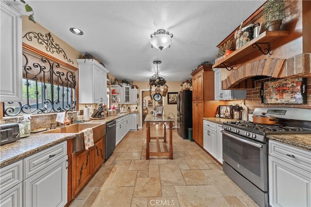 kitchen with light stone countertops, appliances with stainless steel finishes, sink, pendant lighting, and white cabinetry