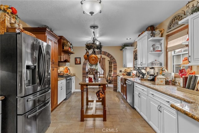 kitchen with a textured ceiling, white cabinetry, stainless steel appliances, and light stone counters