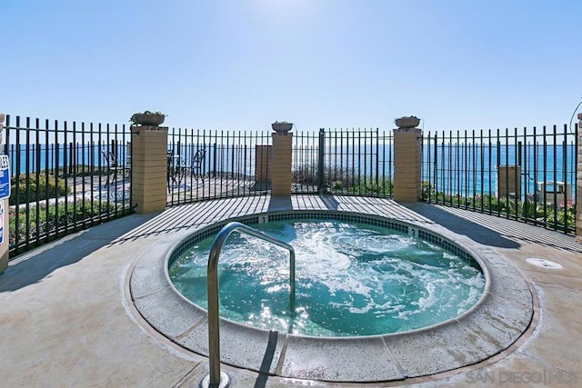 view of swimming pool featuring a water view and a hot tub