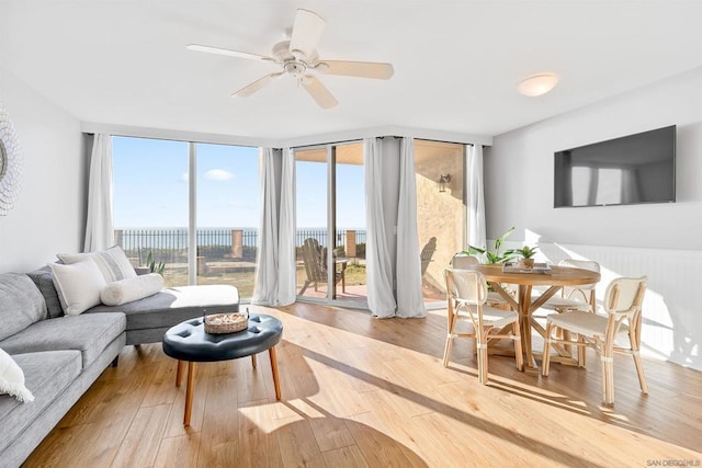 living room featuring ceiling fan, hardwood / wood-style floors, and a wall of windows