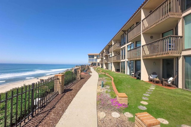 surrounding community with a yard, a water view, and a view of the beach