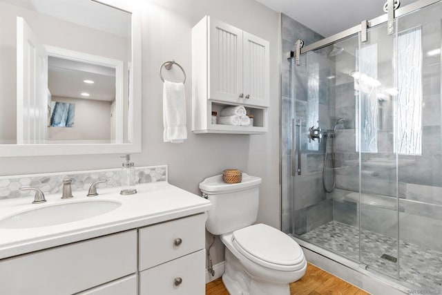 bathroom featuring toilet, vanity, a shower with door, and hardwood / wood-style flooring