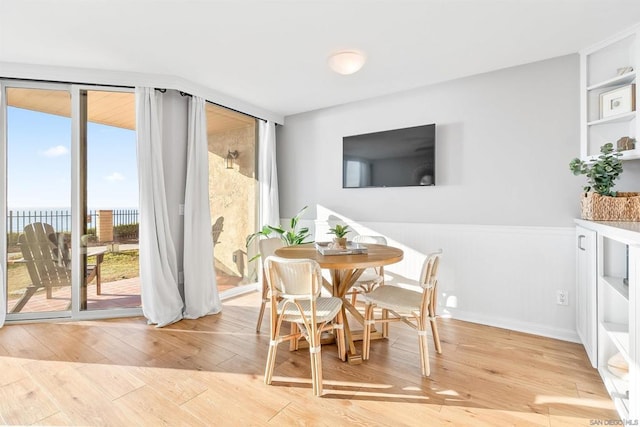 dining room featuring light hardwood / wood-style floors, a water view, and a wealth of natural light