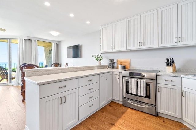 kitchen with kitchen peninsula, white cabinets, light hardwood / wood-style flooring, and stainless steel range with electric stovetop