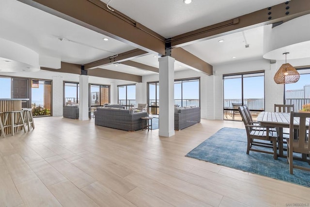 living room with beamed ceiling, light hardwood / wood-style floors, and a healthy amount of sunlight