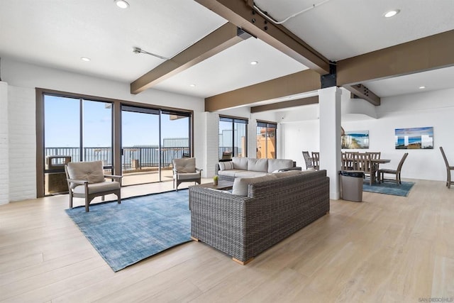 living room featuring beam ceiling, light hardwood / wood-style floors, and a water view