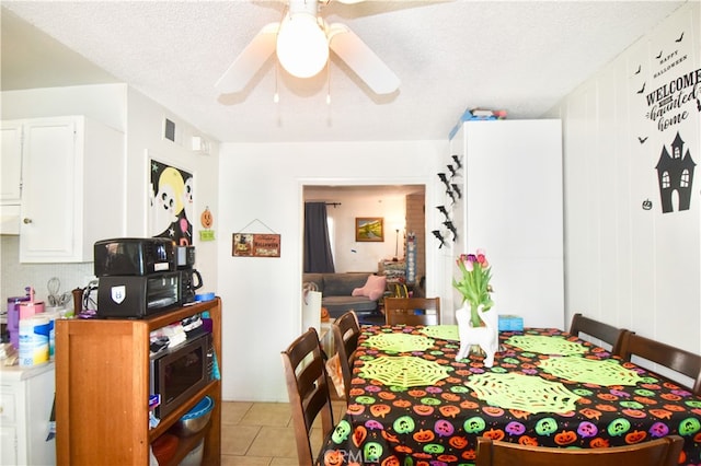 tiled dining area featuring ceiling fan and a textured ceiling