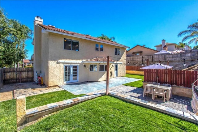 rear view of house with a lawn, a patio area, and french doors