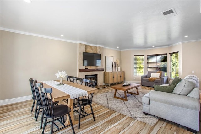 living room with a tile fireplace, light hardwood / wood-style flooring, and ornamental molding