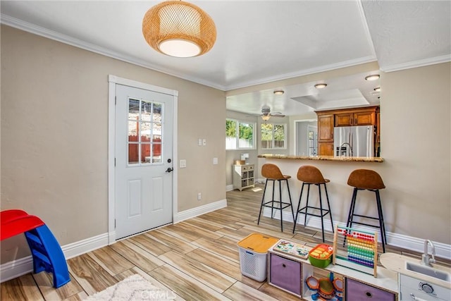 kitchen featuring light hardwood / wood-style flooring, ceiling fan, stainless steel fridge, ornamental molding, and kitchen peninsula